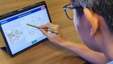 An elderly user takes the pre-dementia drawing test on a digital tablet