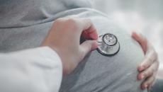 A doctor using a stethoscope to assess a pregnant person