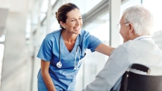 Healthcare provider standing next to a patient in a wheelchair