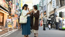 Two persons in the middle of the street talking to each other using a mobile translator app