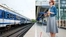 Blind person standing at a train station