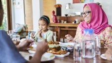 People sitting around a dining room table eating a meal