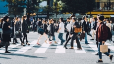 Many individuals walking on a city crosswalk