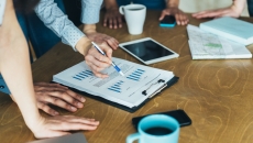 People standing around a table looking at a document