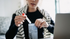 Person in their home sitting in front of a computer putting a test in a bag