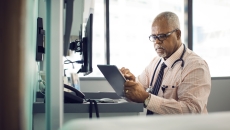 Healthcare provider sitting at a desk while looking at a tablet