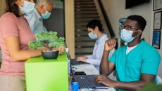 Healthcare providers sitting at a table with two people standing up on the other side