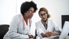 Two doctors looking at data on a laptop