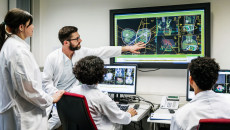 A group of doctors discussing a patient's test results on a large monitor in an office.