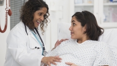 A pregnant woman talking with a doctor in a hospital.