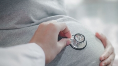 A health professional placing a stethoscope on a pregnant belly