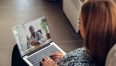 A person talking to a doctor via a video chat on a laptop.