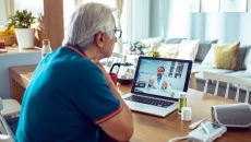 A person talking to a doctor via a video chat on his laptop.