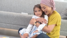 Two people sitting on the floor next to a couch with one wearing a head scarf