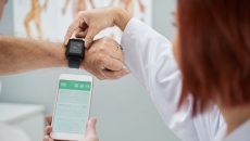 A doctor helping a patient synchronise their smartwatch with a mobile health app
