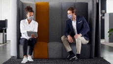 Woker in mask showing tablet to other worker in mask