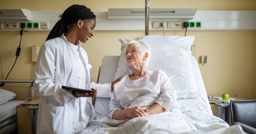 Healthcare provider talking to patient in a bed