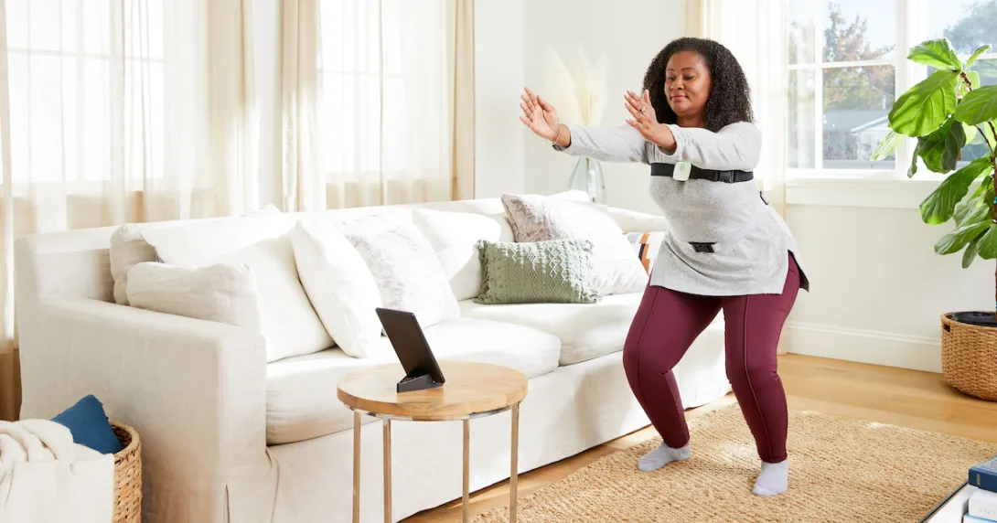 A woman wearing Hinge sensors performing exercises guided via a tablet