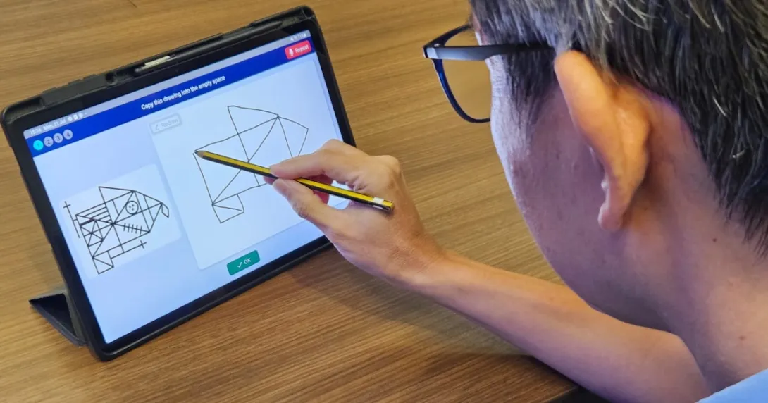 An elderly user takes the pre-dementia drawing test on a digital tablet