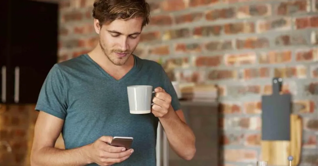 Person holding a cellphone and a cup of coffee