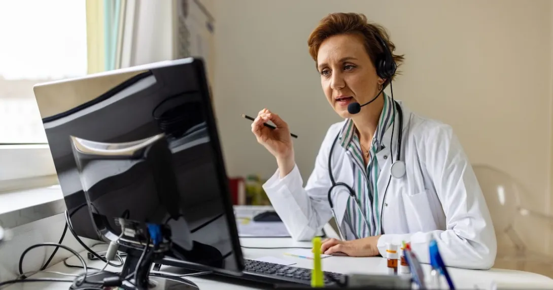 A doctor uses headphones with a mic in a call 
