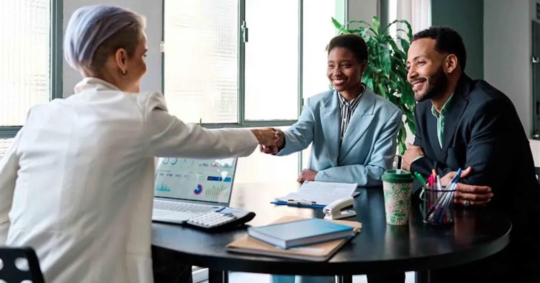 Businessperson shaking hands with a client while another person watches