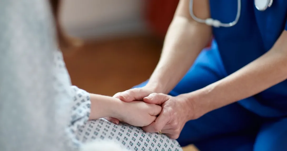 A nurse holding a patient's hands