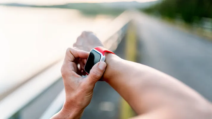 Person adjusting their fitness wearable while exercising outside
