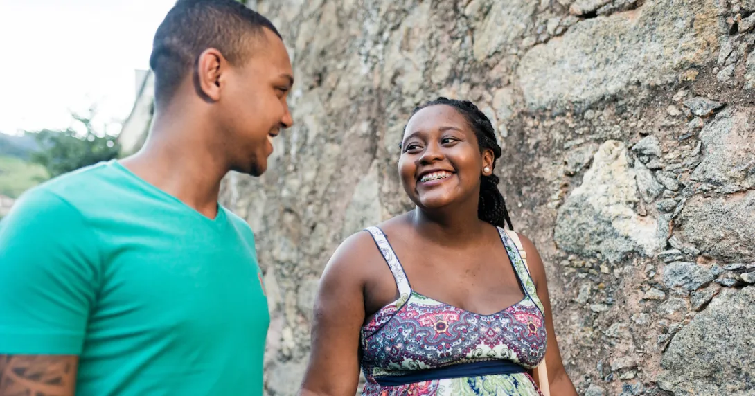 Two people walking together while looking at each other and smiling