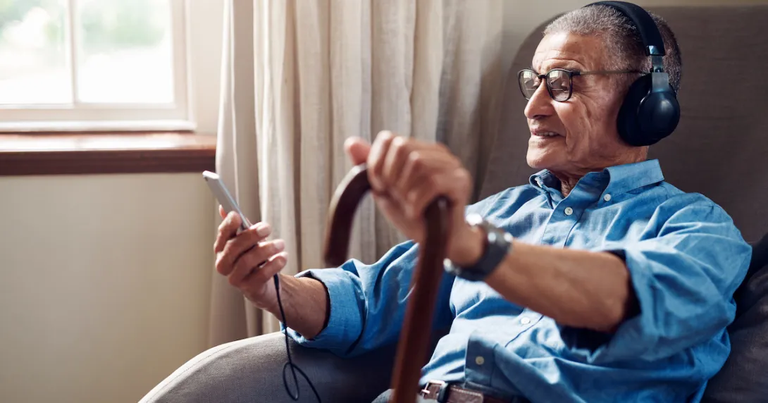 Person sitting, holding a cane, looking at their phone