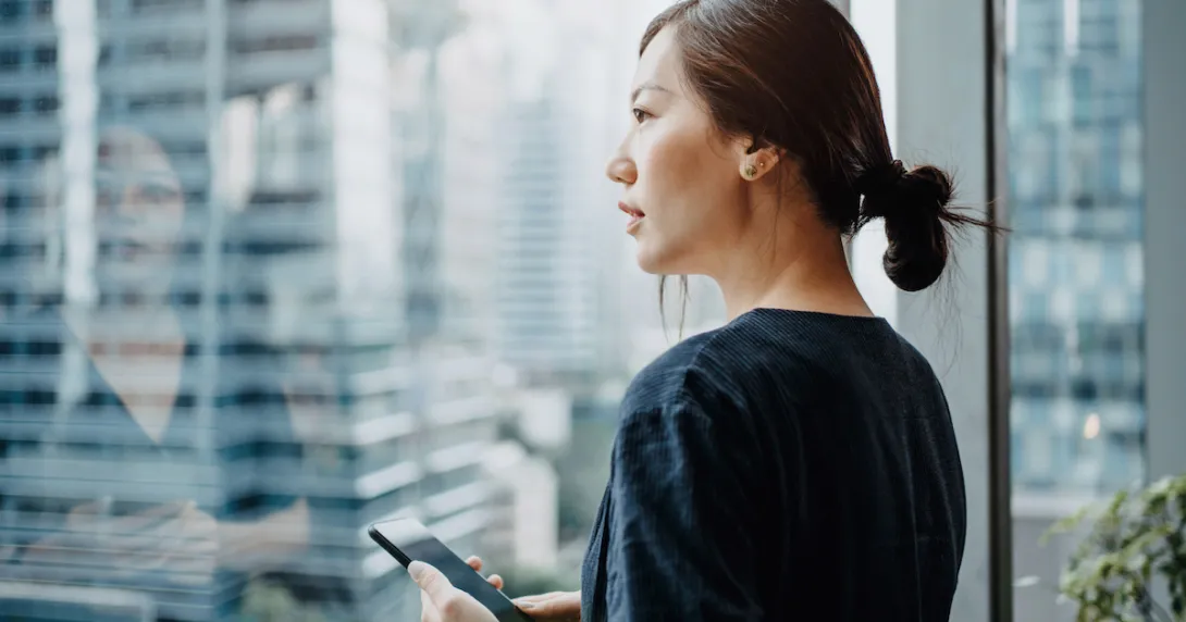 Person standing in front of a window holding a phone