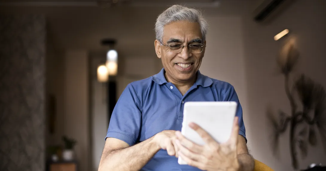 Person wearing a blue shirt and holding a tablet in the living room of a home