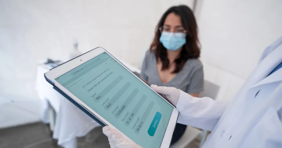 Healthcare provider on a tablet with a patient sitting in a room