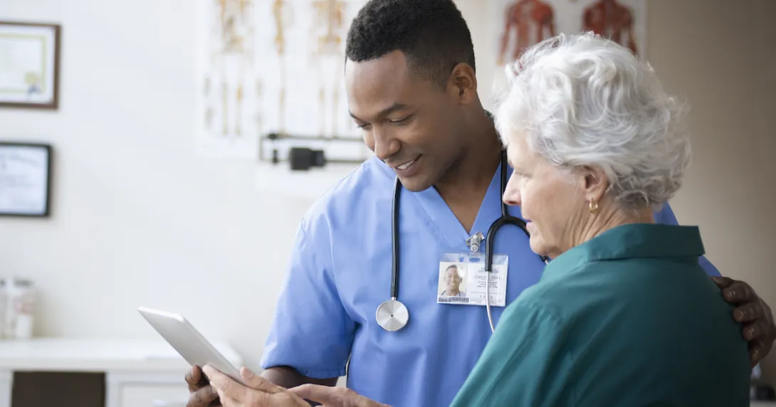 Healthcare provider talking to a patient while showing them a tablet