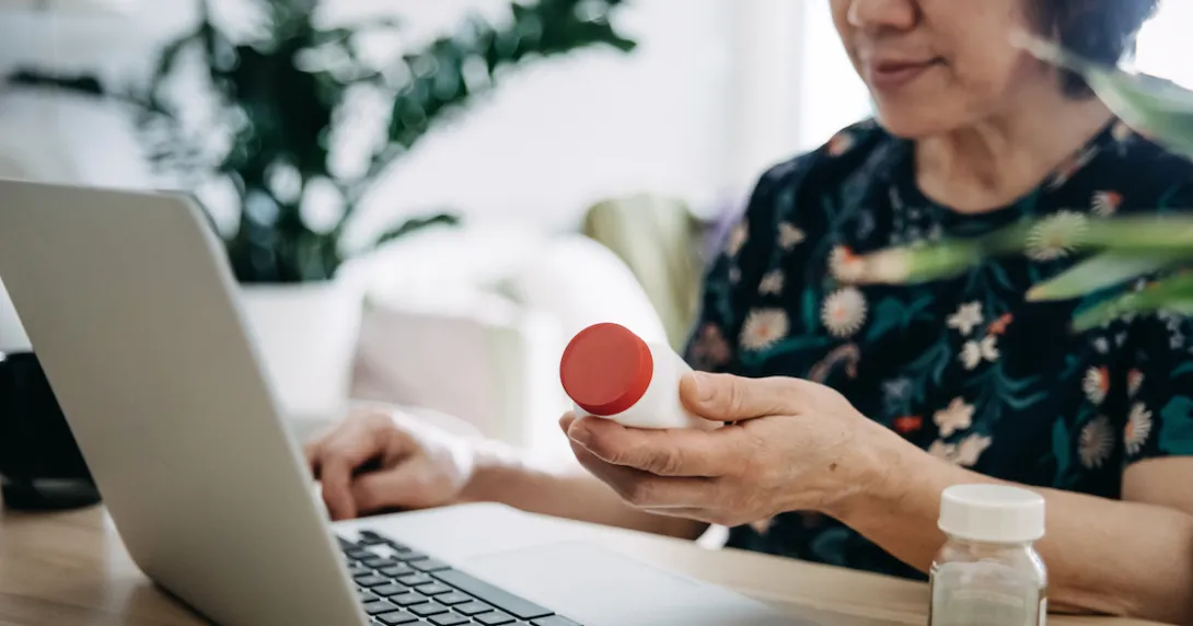 Person looking at a prescription bottle while on a computer
