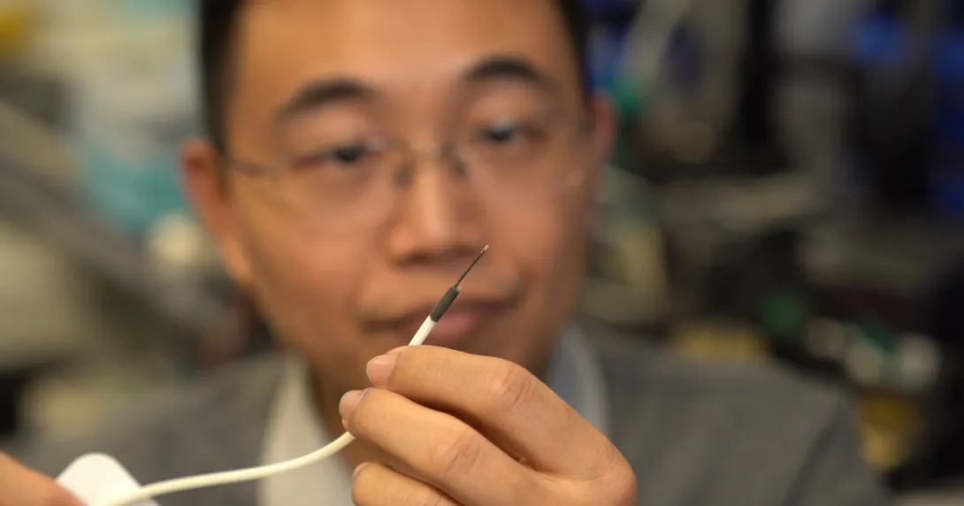 A researcher holding a small-scale surgical robot