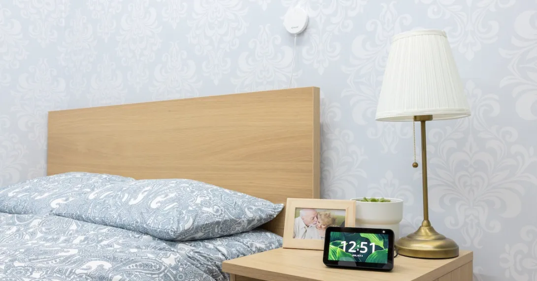 An Alexa device on a bedside table with a Vayyar sensor above the bed.