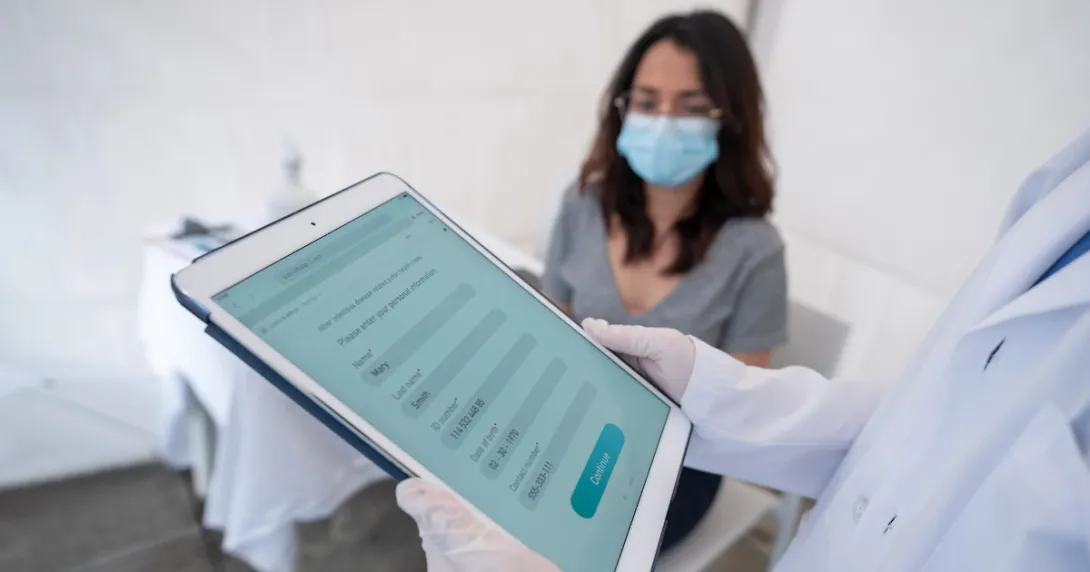 Person being registered for a COVID-19 vaccine at an immunization stand with a tablet computer.