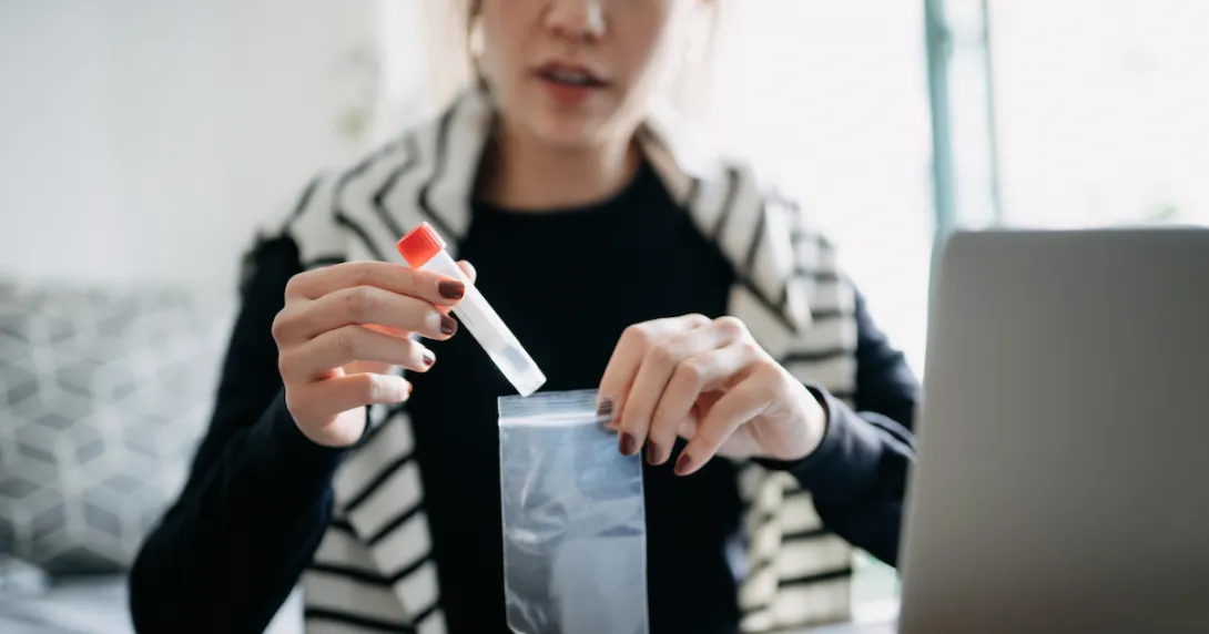 A person at home puts a lab sample into a bag for shipping