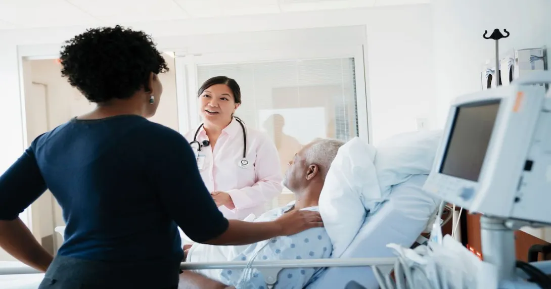 A doctor talks to a man and his loved one at a hospital