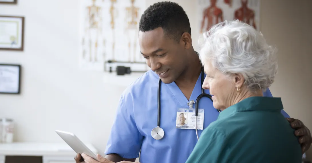 A doctor and a patient looking at information on a tablet.