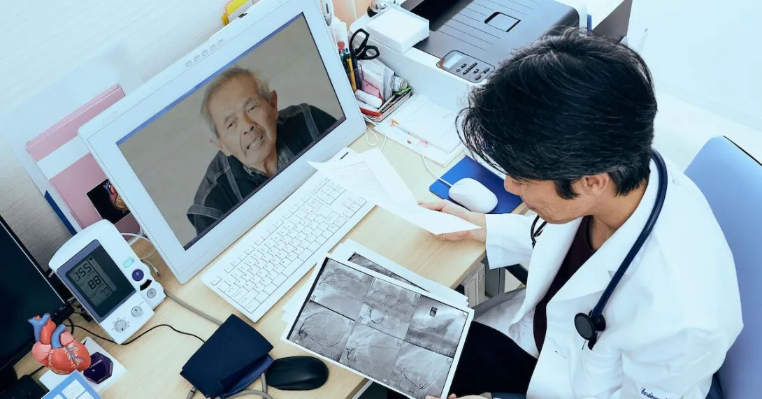 A doctor looking at imaging results while consulting with a patient on his laptop