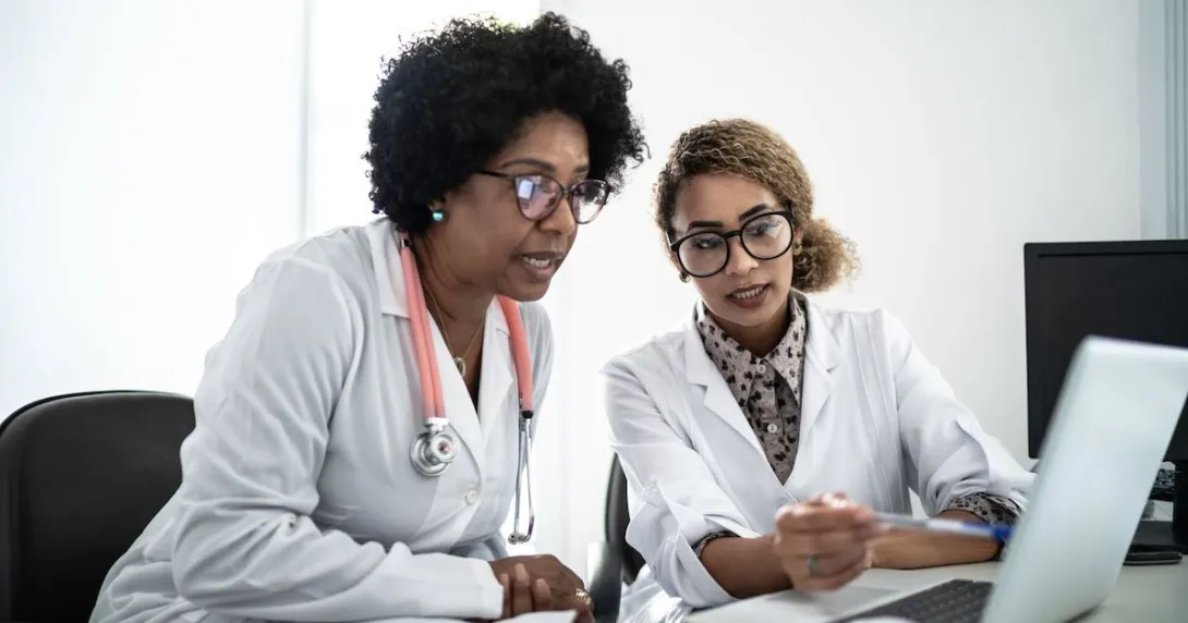Two doctors looking at data on a laptop