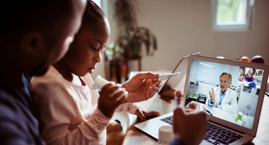 A father and daughter talking to a provider using a laptop