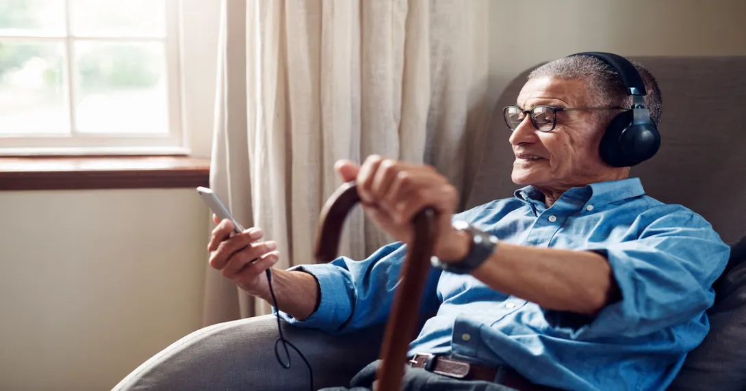 A person wearing headphones, using a smartphone and wearing a watch in the home