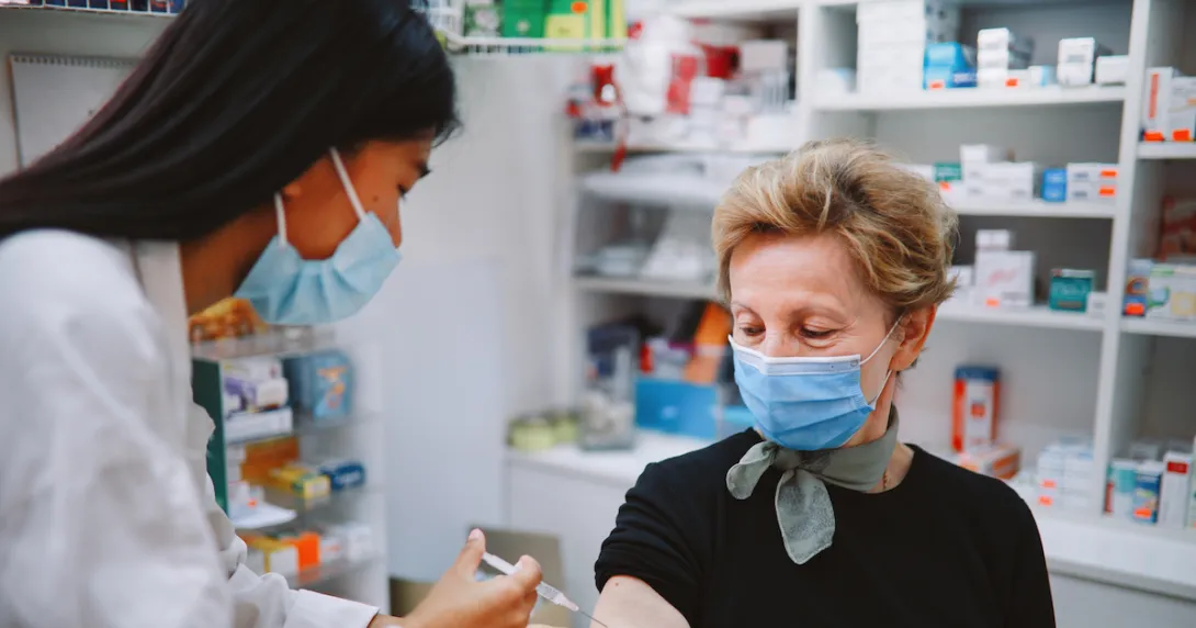 An older person receiving a vaccine in a pharmacy.