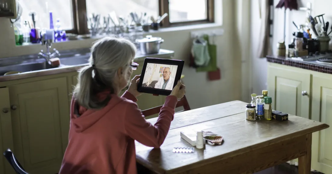 A woman talking to a provider through a video call on a tablet.