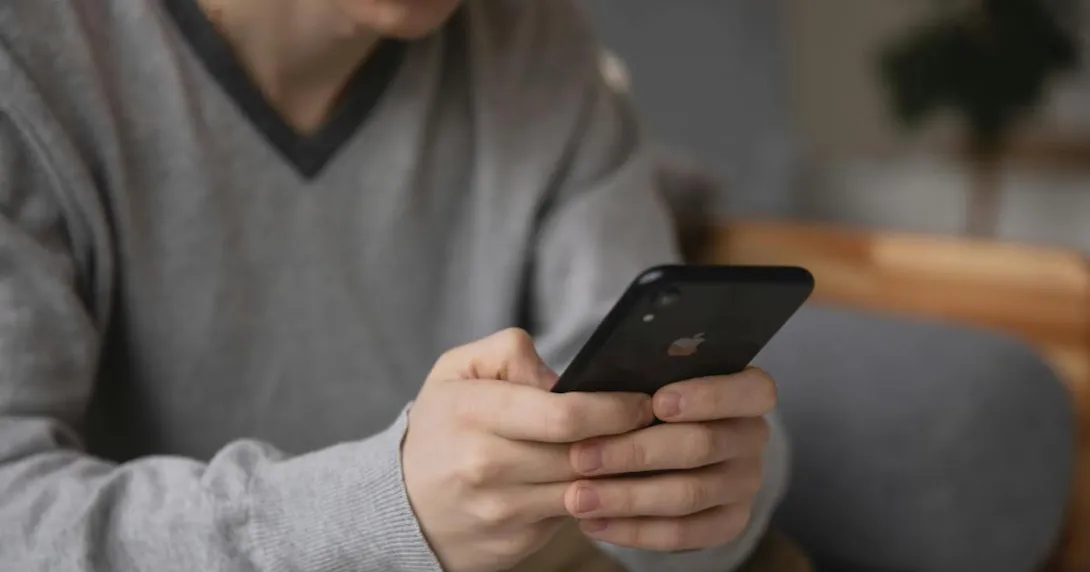 A person sitting in a couch using a smartphone