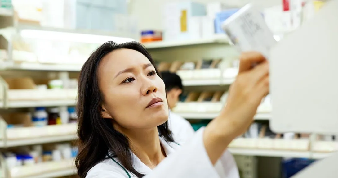 A pharmacist pulling a medication off a shelf.