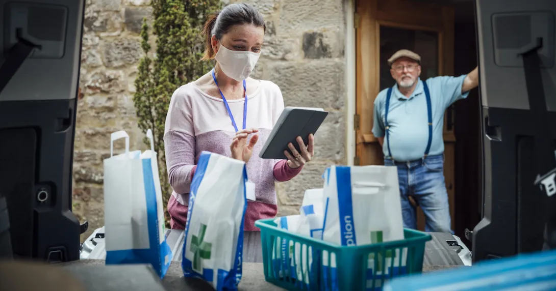 A woman wearing a mask delivering medications.